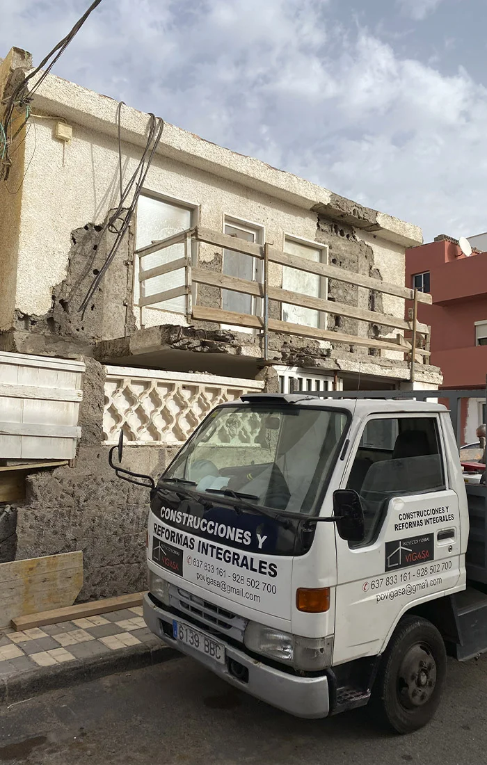 Vivienda en proceso de rehabilitación con partes de la fachada demolidas y camión rotulado de Vigasa estacionado al frente. Obra de reformas integrales en Agüimes, Gran Canaria. Foto propiedad de Vigasa.