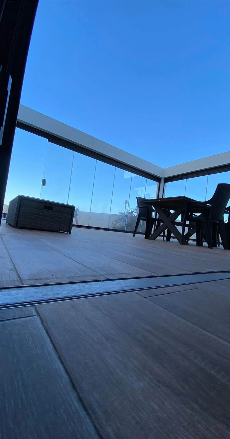 Terraza con suelo porcelánico imitación madera, cerramiento de cristal y mobiliario exterior moderno. Proyecto de reformas parciales. Foto propiedad de Vigasa.